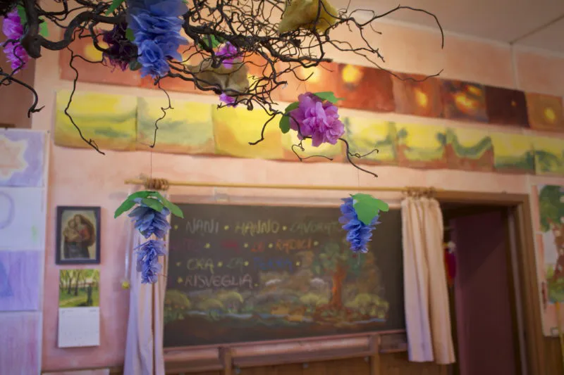 Un'aula decorata con fiori e un fregio dipinto sopra la lavagna