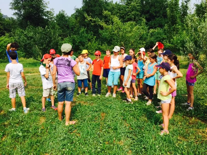 Bambini in cerchio su un prato con le educatrici