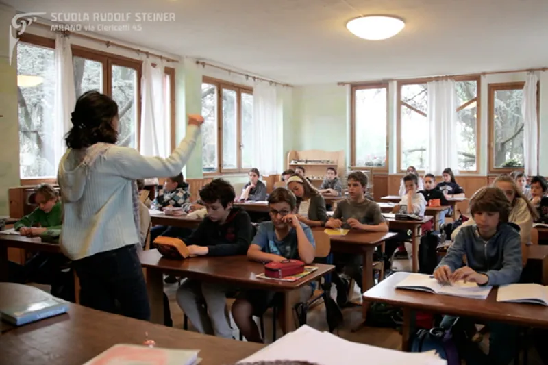 Una maestra spiega davanti alla classe in un'aula luminosa