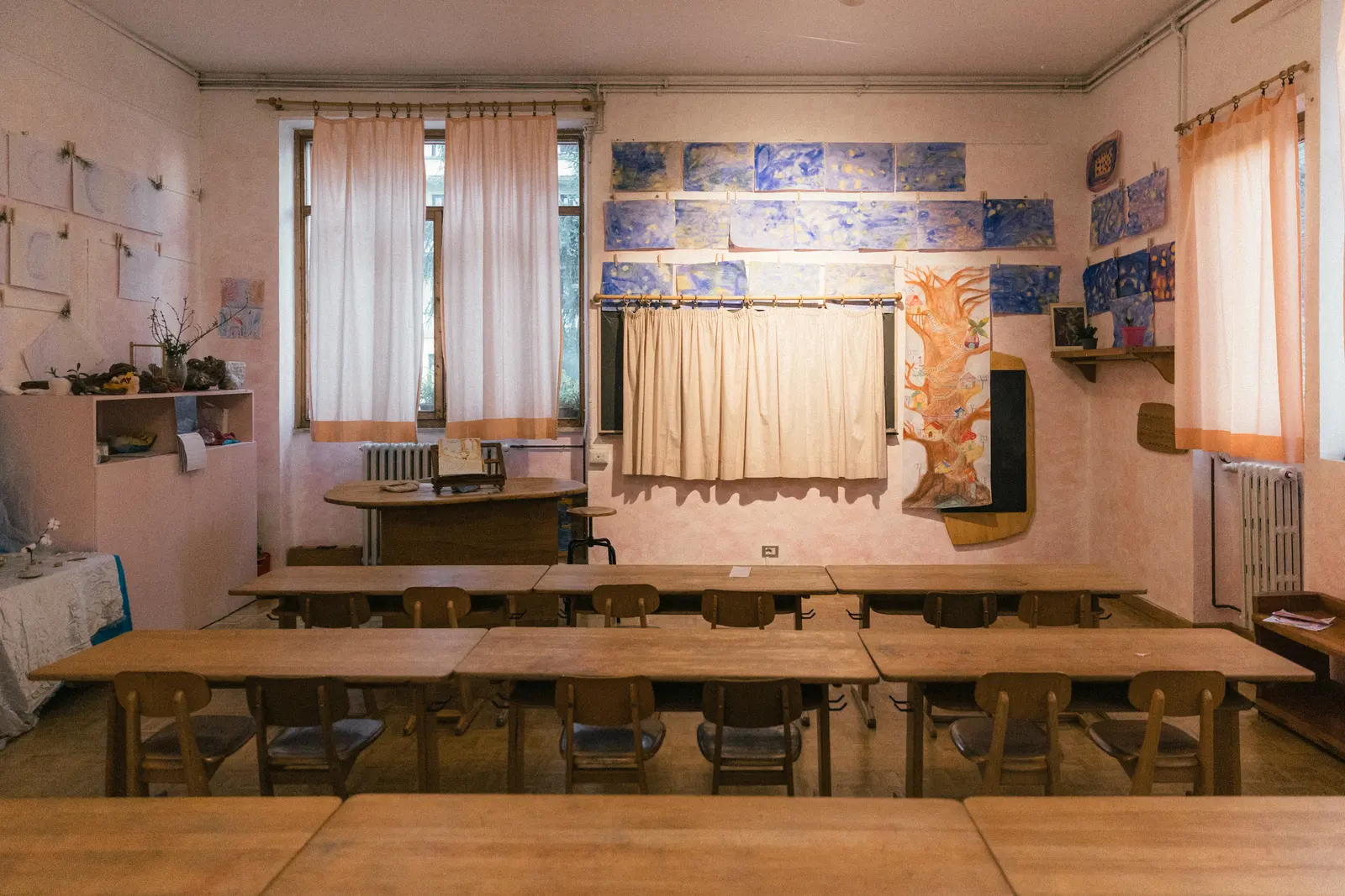 Un’aula luminosa con banchi in legno e tende chiare
