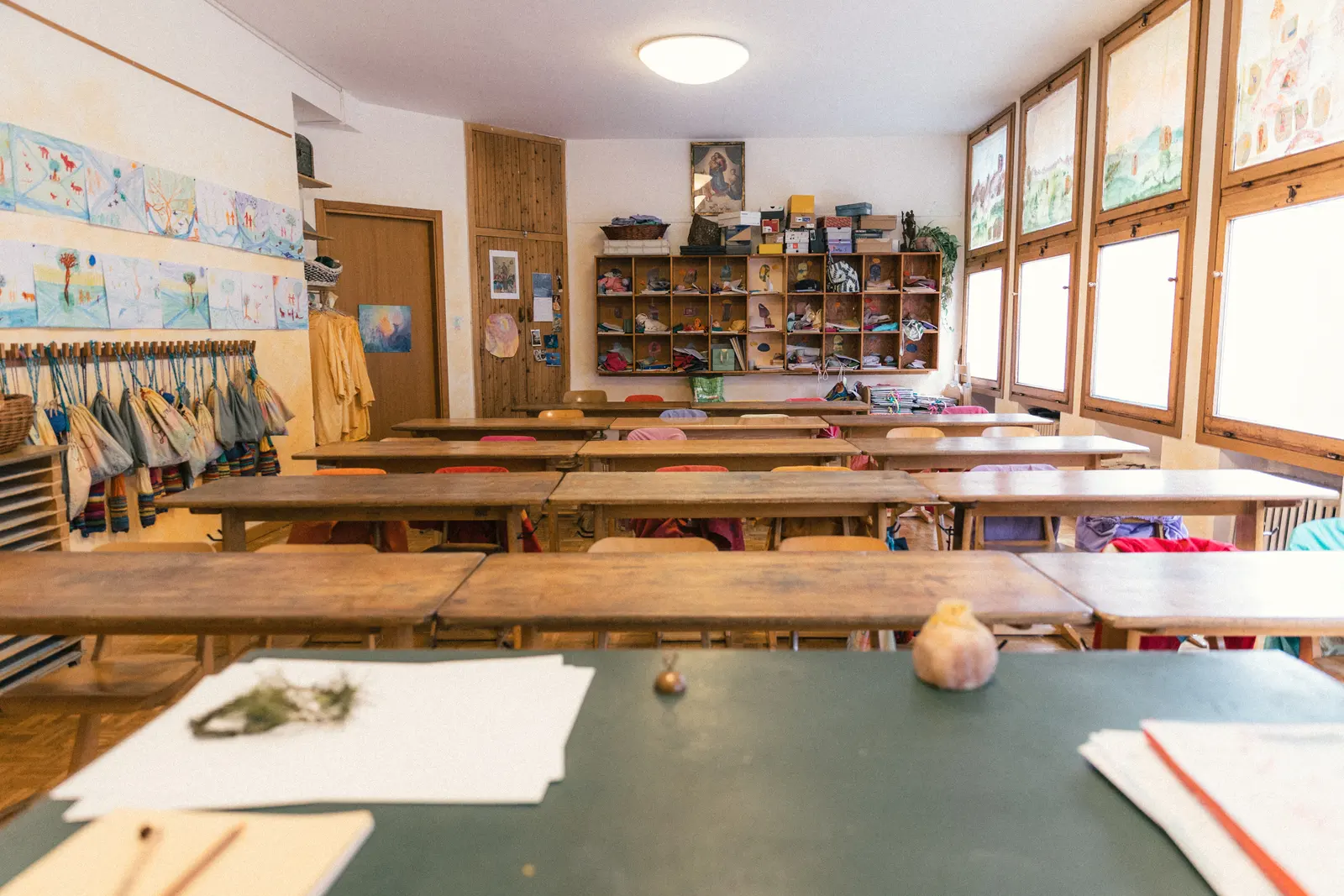 Banchi di un’aula con quaderni, disegni e materiali naturali