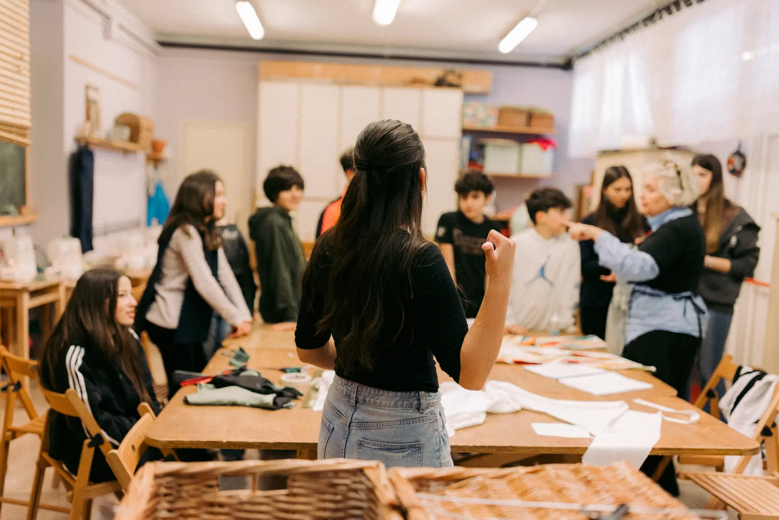 Studenti lavorano ai costumi tra tavoli, stoffe e materiali