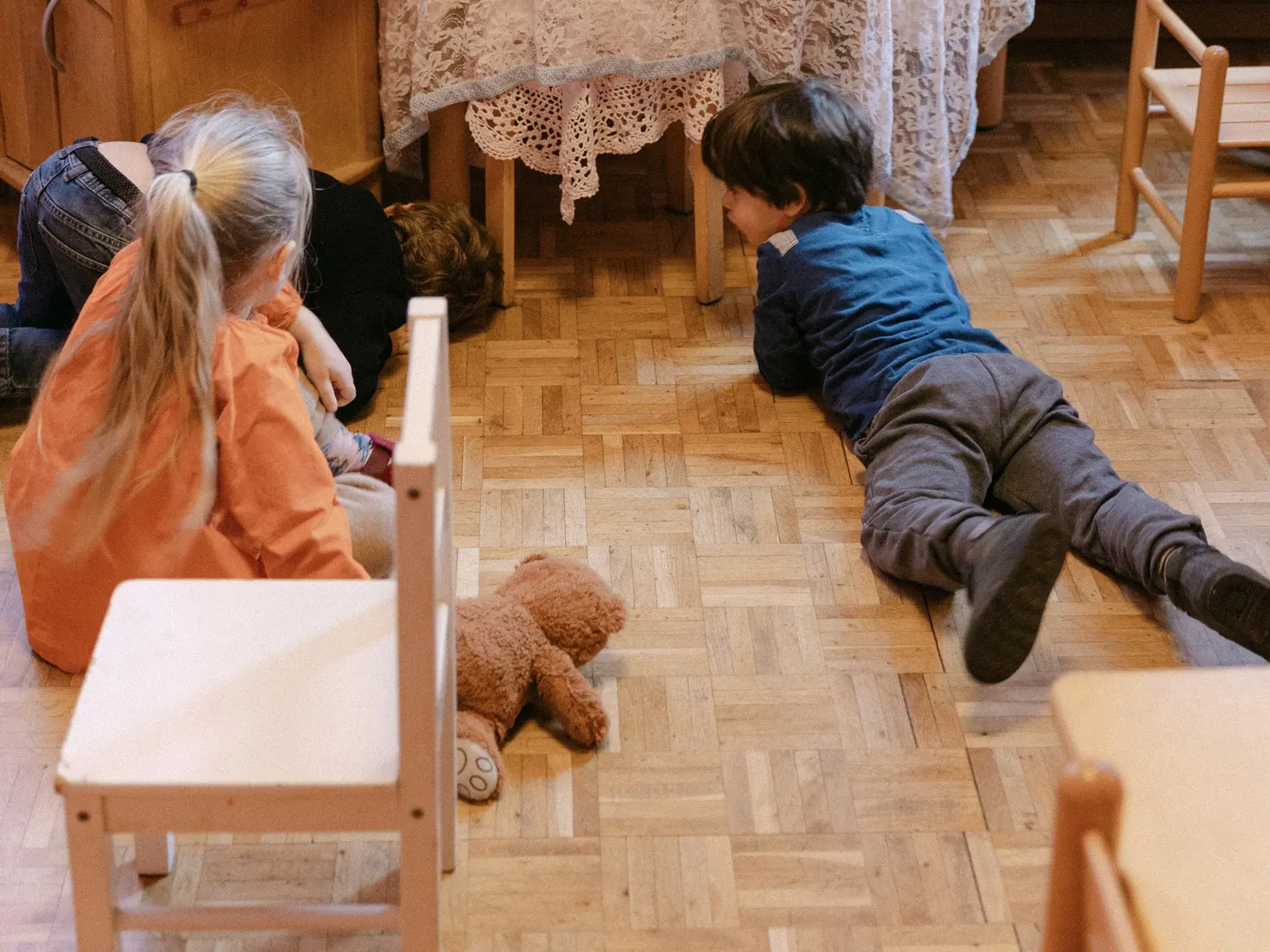 Bambini giocano sul pavimento dell’aula con un cavallo di legno