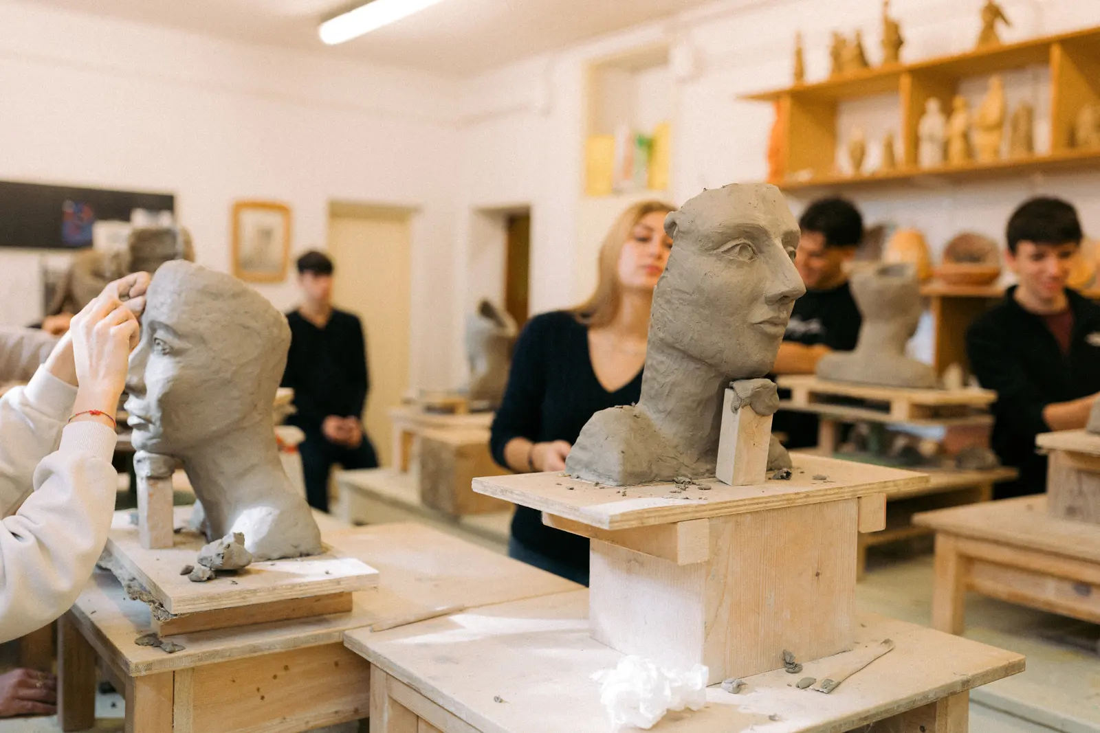Ragazzi lavorano a busti in argilla nel laboratorio di scultura
