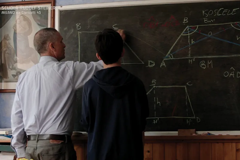 Un maestro e un alunno lavorano insieme alla lavagna di geometria