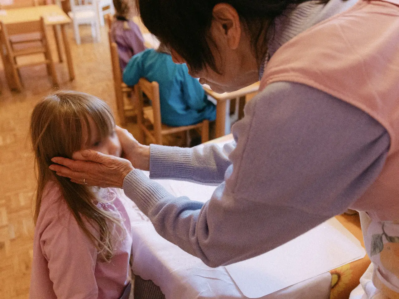 Un’adulta accompagna una bambina con un gesto di attenzione