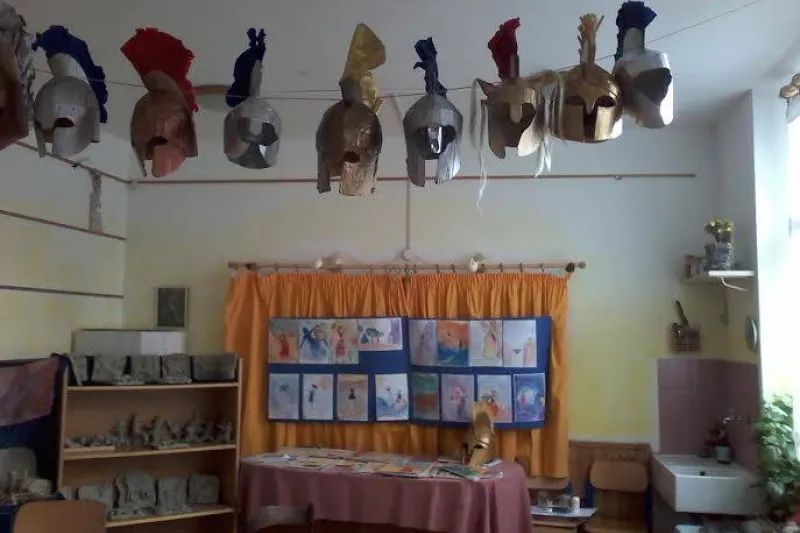 Un'aula con gli elmi di cartapesta costruiti dagli alunni appesi alla parete