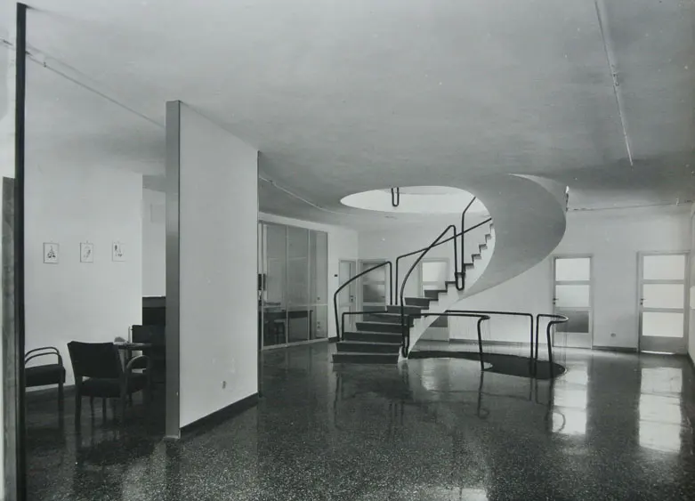 Fotografia in bianco e nero di un salone con scala a chiocciola