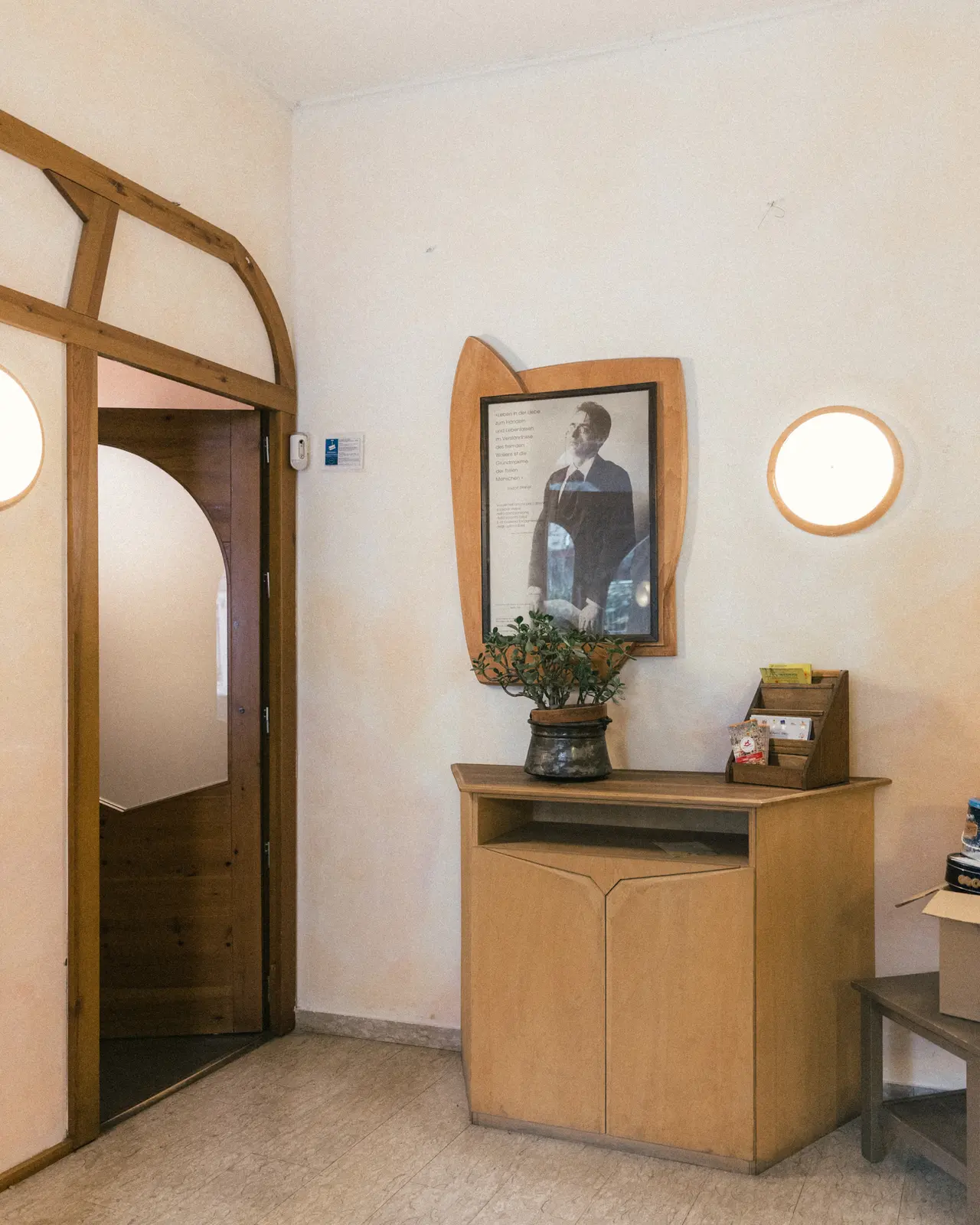 Un angolo della scuola con un ritratto di Rudolf Steiner, una porta ad arco e una finestra rotonda